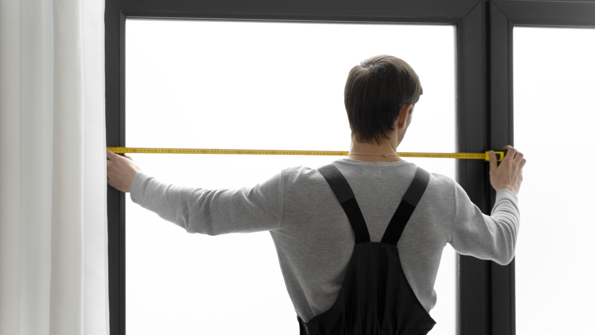 Un professionnel prend les mesures nécessaires à l'installation de nouvelles menuiseries